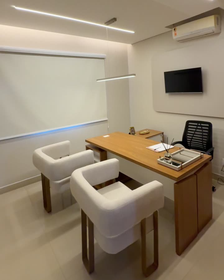 Consultório com mesa, poltronas e janela